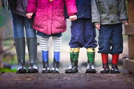 Cuatro niños de frente y sin enseña la cabeza cogidos de las manos.