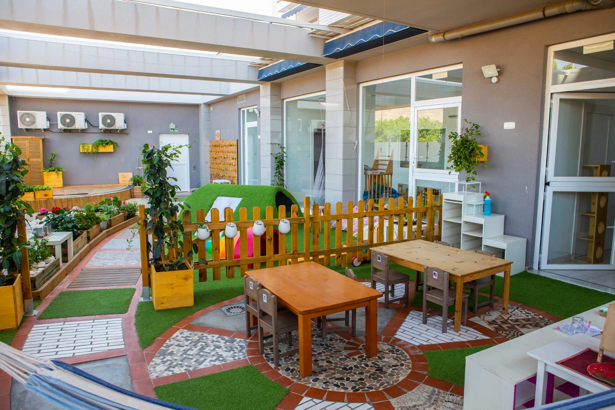 El patio interior del hogar con mesas y sillas a la altura de los peques.